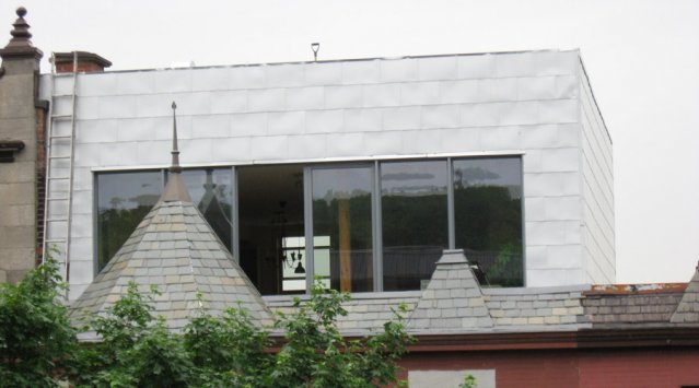 Une maison ancienne additionnée d'un étage avec toit vert. Photo Écohabitation.