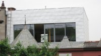 Une maison ancienne additionnée d'un étage avec toit vert. Photo Écohabitation.