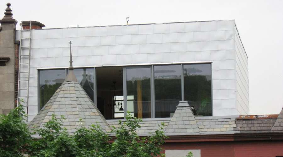 Une maison ancienne additionnée d'un étage avec toit vert. Photo Écoha