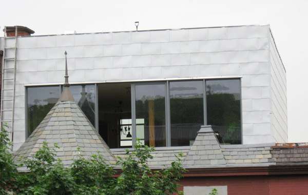 Une maison ancienne additionnée d'un étage avec toit vert. Photo Écoha