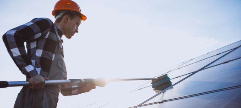 Homme qui nettoie des panneaux solaires